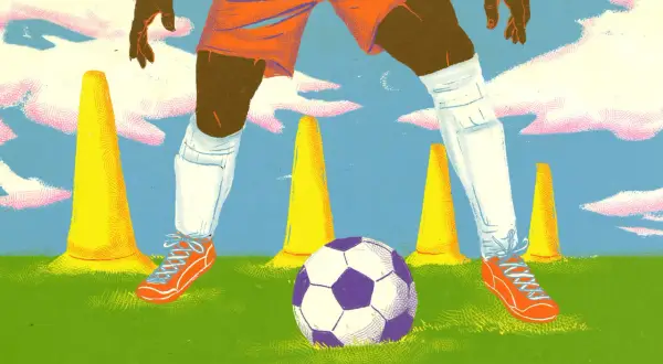Jugador de fútbol en entrenamiento, rodeado de conos amarillos y un balón morado y blanco.