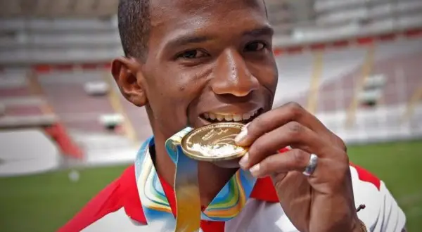 Andy Martínez, atleta peruano, muerde su medalla de oro, símbolo de su victoria en el estadio.