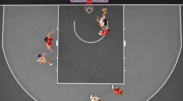 Jugadoras de baloncesto 3x3 compiten en la cancha. Se aprecian diferentes tipos de baloncesto en acción, con una lanzando a canasta.