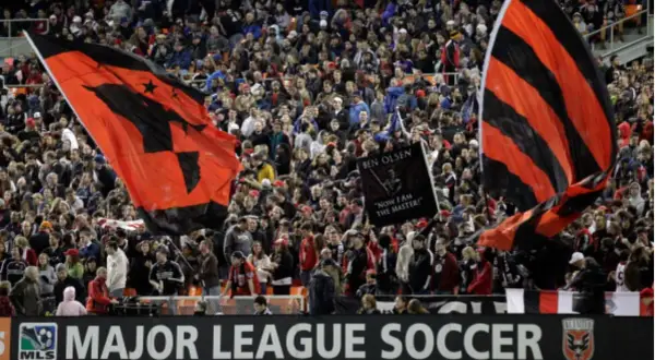 Aficionados ondean banderas rojas y negras en un partido de la liga futbol eeuu.
