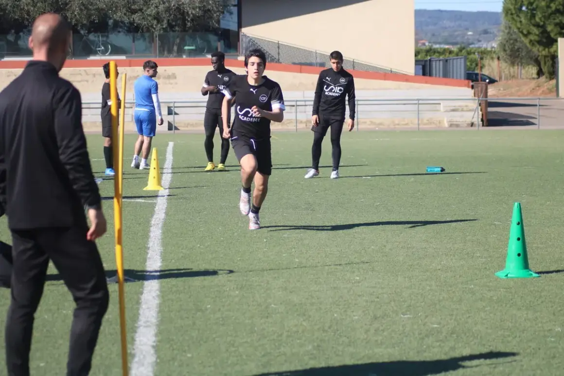 Jóvenes futbolistas realizan pruebas físicas en campo. Un entrenador de fútbol nivel 1 supervisa el entrenamiento.