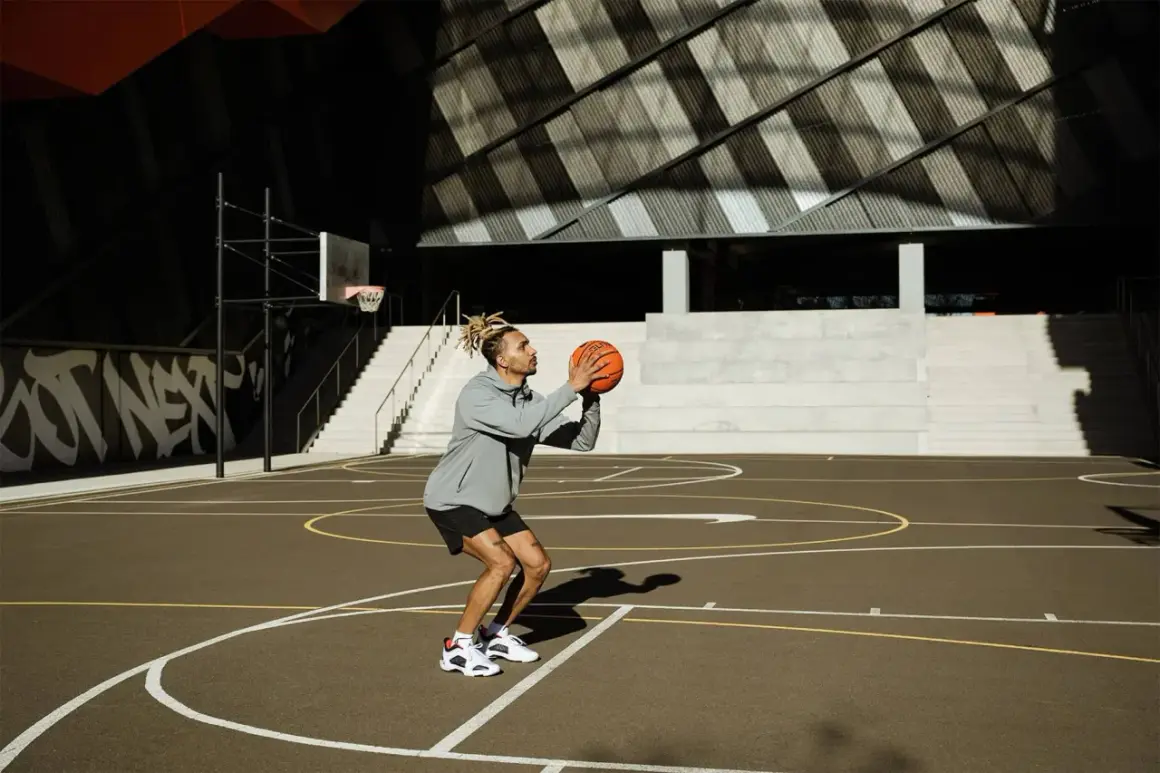 Hombre concentrado en un tiro libre de baloncesto en una cancha exterior.