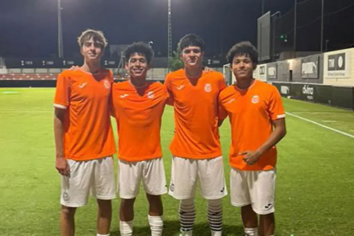 Cuatro jóvenes futbolistas del Olímpico de Villarrobledo posan sonrientes en el campo de césped artificial.