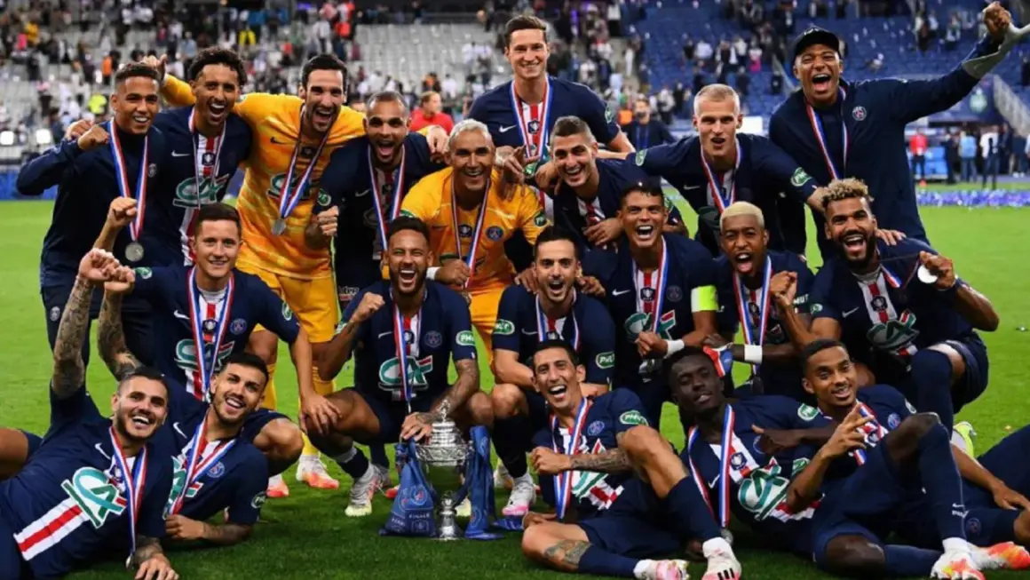 Jugadores del PSG celebran con trofeo y medallas tras ganar la liga francesa de fútbol.
