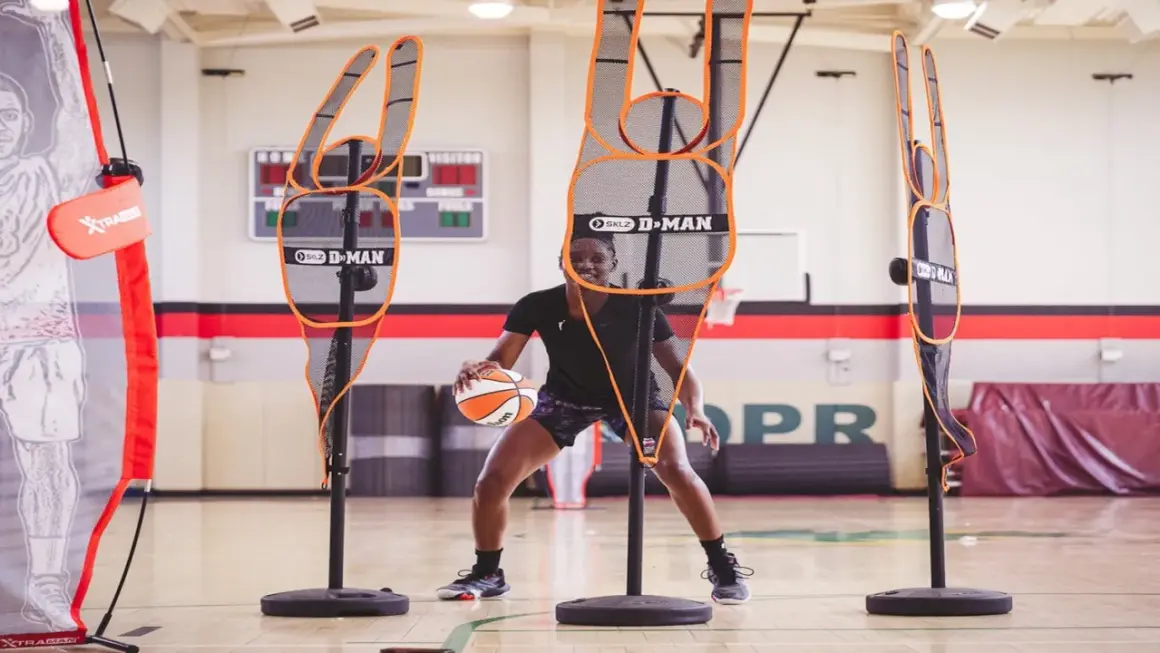 Jugador de baloncesto practica sus tiros libres rodeado de maniquíes de defensa.