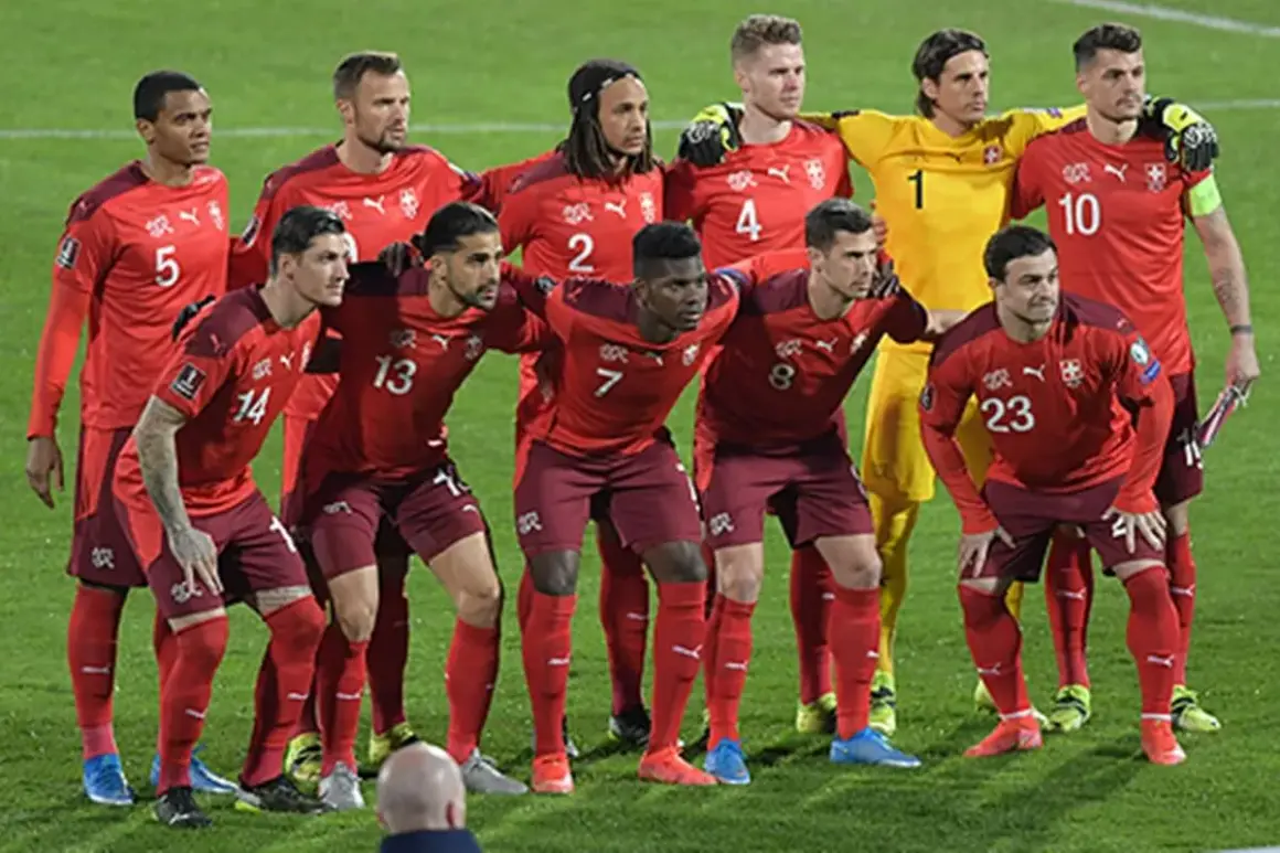 El equipo de fútbol suizo posa en el campo. Los jugadores lucen sus uniformes rojos, listos para el partido.