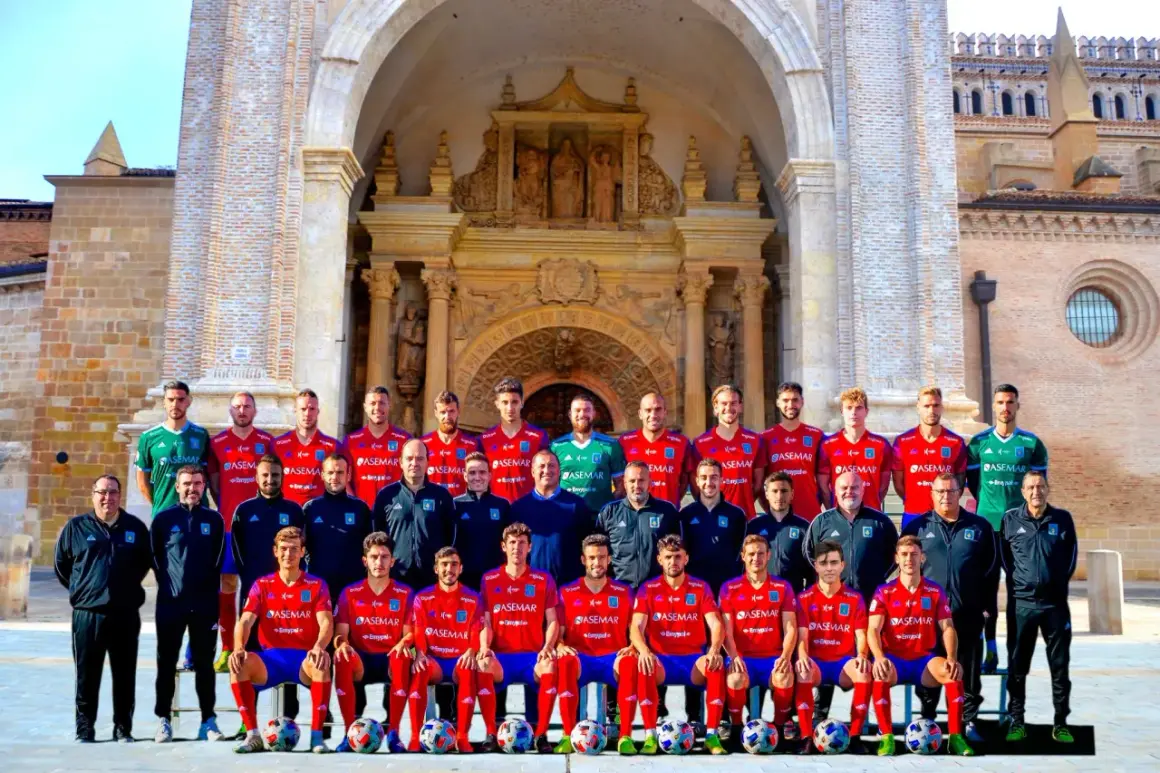 El equipo del Atlético Tarazona posa para una foto grupal frente a una fachada histórica.