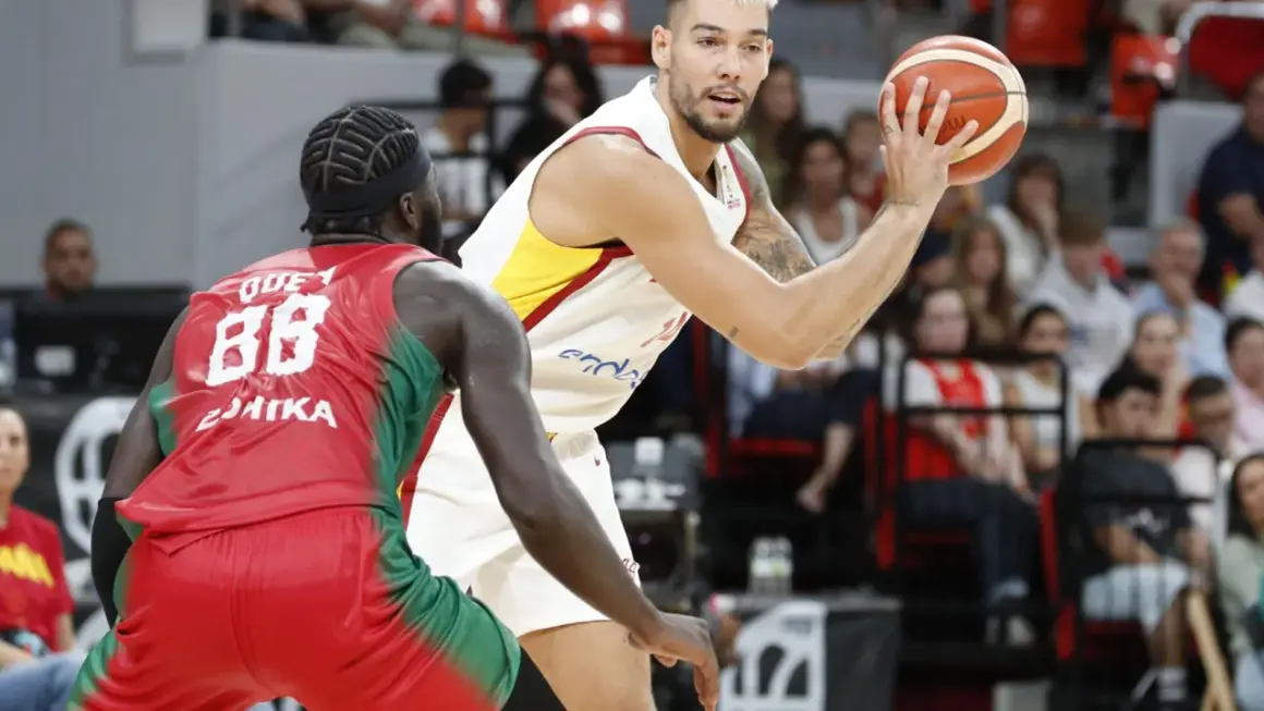 Jugador de baloncesto con el balón en mano, listo para su primera canasta de baloncesto, defendido por un oponente.