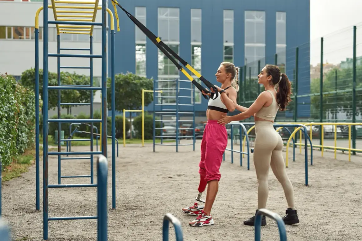 Dos mujeres entrenan en un gimnasio al aire libre. Una usa un sistema de entrenamiento en suspensión para un microciclo de impacto.