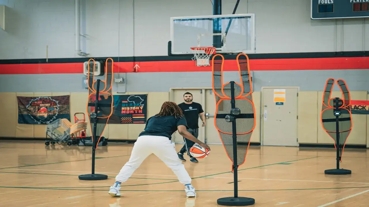 Jugador de baloncesto practica dribling entre maniqu&iacute;es, realizando ejercicios anal&iacute;ticos para mejorar su juego.