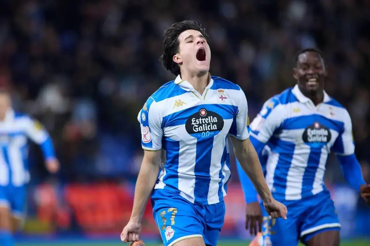 Jugador celebra gol con euforia. Viste camiseta a rayas azules y blancas, típica de equipos de tercera división de España.