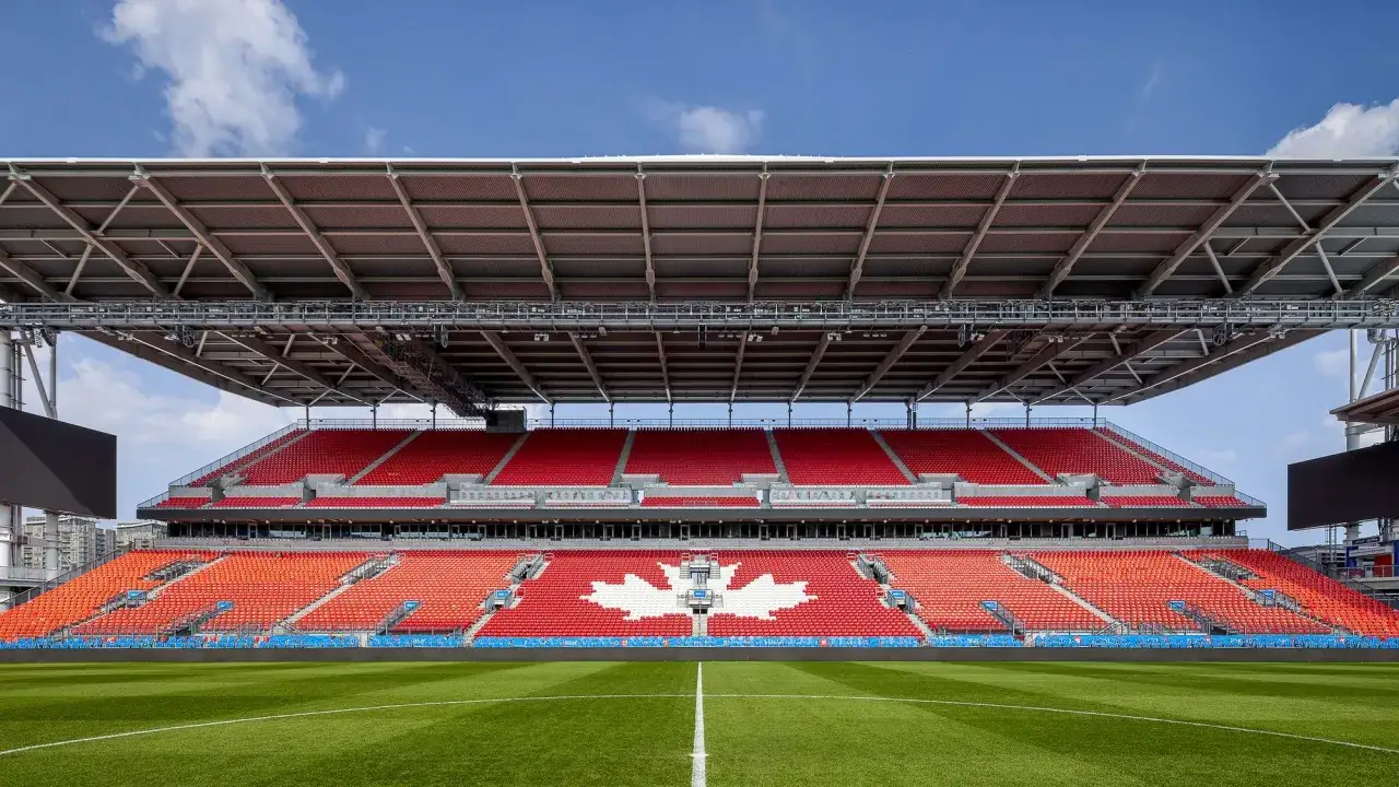 Estadio con asientos rojos y naranjas, destacando un gran arce blanco en las gradas. Listo para la liga de Canadá.