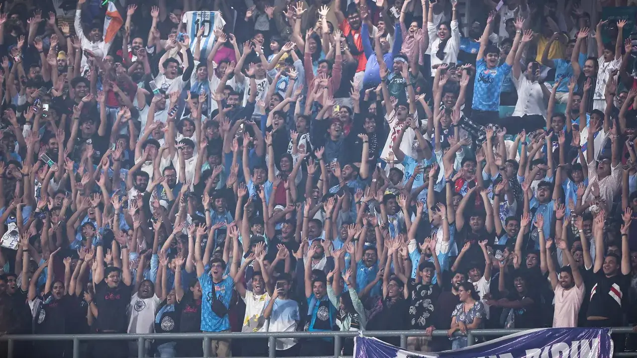 Multitud animada en un partido de la liga india de fútbol, con aficionados alzando las manos y vistiendo camisetas de Argentina.