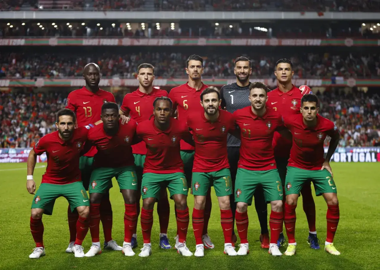 El equipo de la Federação Portuguesa de Futebol posa para una foto en el campo, luciendo sus uniformes rojos y verdes.