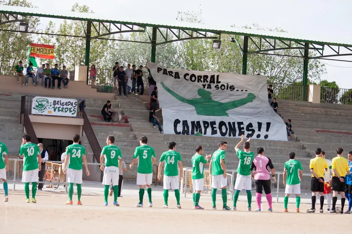 Jugadores del CF Almaguer celebran su victoria como campeones, con una pancarta gigante y el apoyo de las 