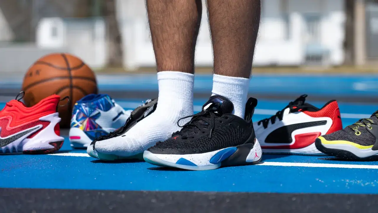 Un jugador de baloncesto con el pie mas grande posa con varias zapatillas deportivas.