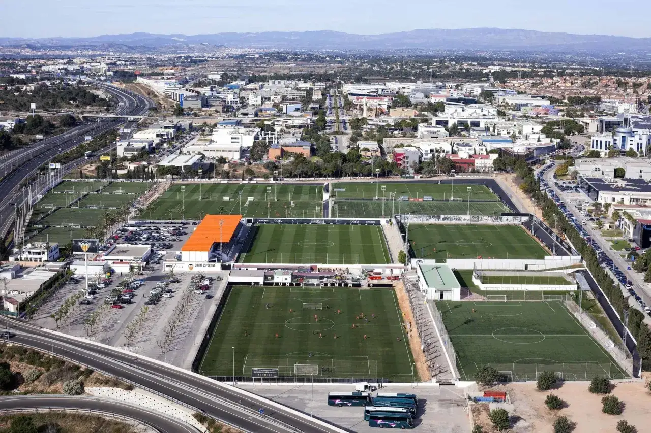 Vista aérea de la ciudad deportiva Valencia, con múltiples campos de fútbol, edificios y una autopista.