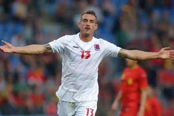 Jugador de la luxemburgo seleccion celebra un gol, con el número 13 en su camiseta blanca.