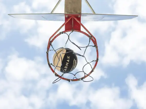 Un balón de baloncesto a punto de entrar en la canasta. La altura reglamentaria de a cuantos metros está la canasta de baloncesto del suelo es de 3.05 metros.