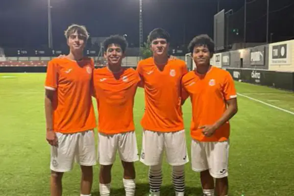 Cuatro jóvenes futbolistas del Olímpico de Villarrobledo posan sonrientes en el campo de césped artificial.