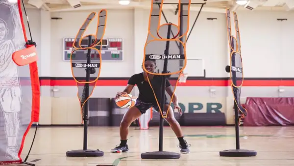 Jugador de baloncesto practica sus tiros libres rodeado de maniquíes de defensa.