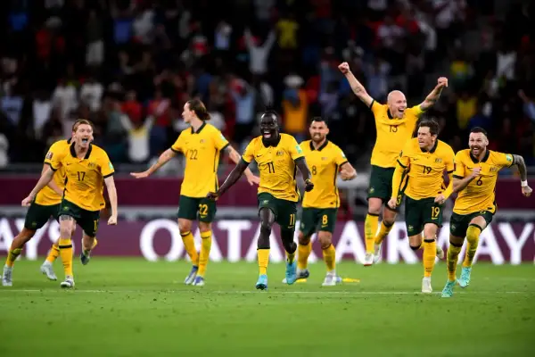 Jugadores de la Australia seleccion celebran con euforia en el campo de juego, con los brazos en alto y sonrisas de victoria.
