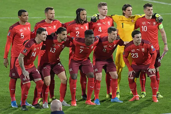 El equipo de fútbol suizo posa en el campo. Los jugadores lucen sus uniformes rojos, listos para el partido.