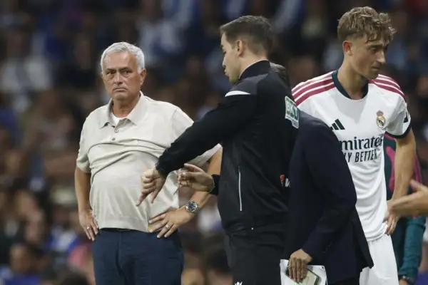 Entrenador jugador con gesto de desaprobación. El entrenador, con su mano, señala hacia abajo, mientras un jugador del Real Madrid observa.