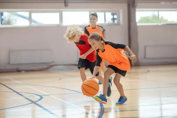 Niños jugando al baloncesto en una cancha interior. La edad infantil es clave para aprender este deporte.