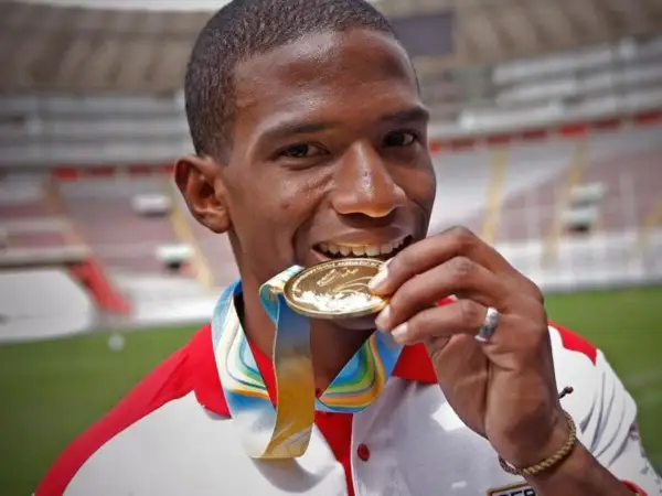 Andy Martínez, atleta peruano, muerde su medalla de oro, símbolo de su victoria en el estadio.