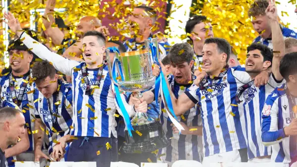 Jugadores celebran con la copa tras ganar la final Copa del Rey. Confeti dorado cae sobre ellos.